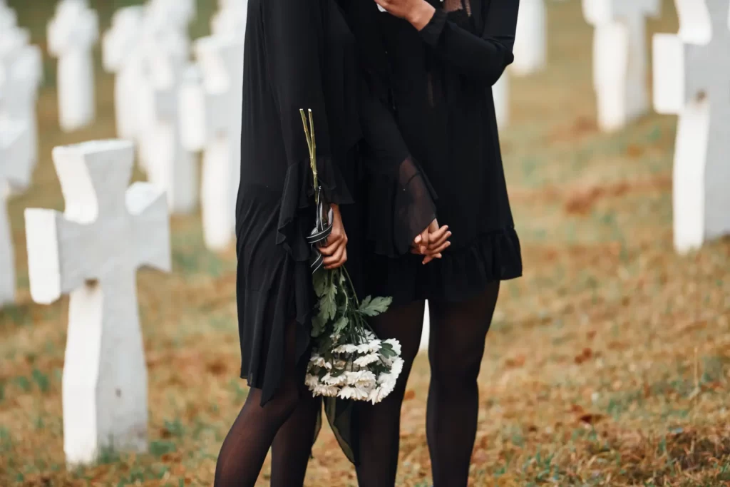women holding flowers at funeral cemetery
